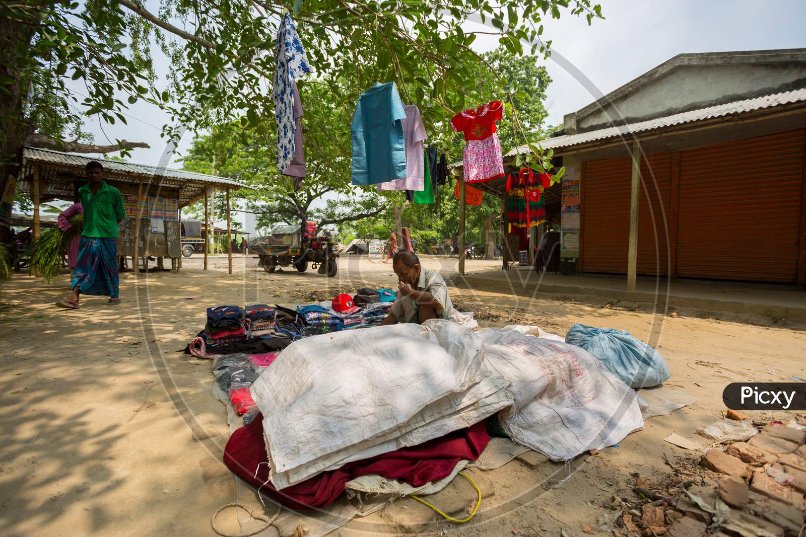Bangladesh - May 19, 2019: A Rural Village Businessman Selling Cloth And Products To Hang Up On The Tree Trunk, Meherpur, Bangladesh.