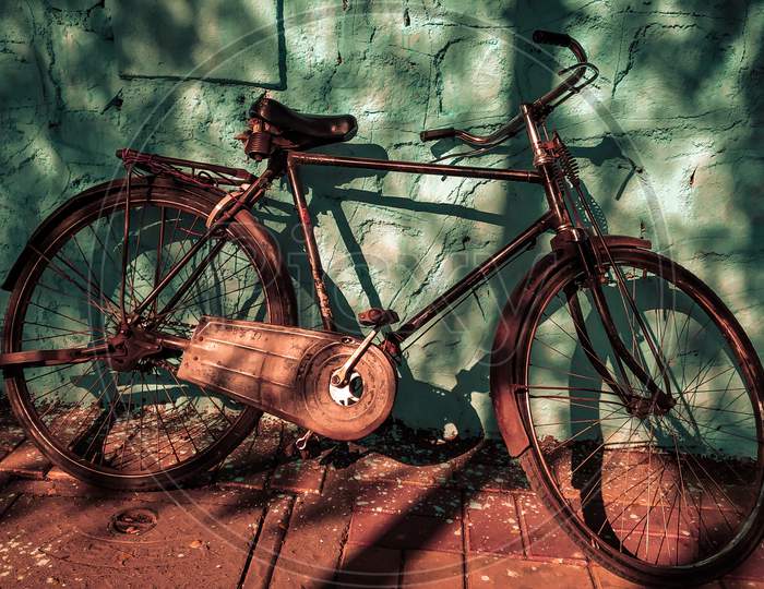 Old Vintage Rustic Metallic Bicycle With Blue Wall As A Background With Light And Shadow Can Be Used As A Advertising.