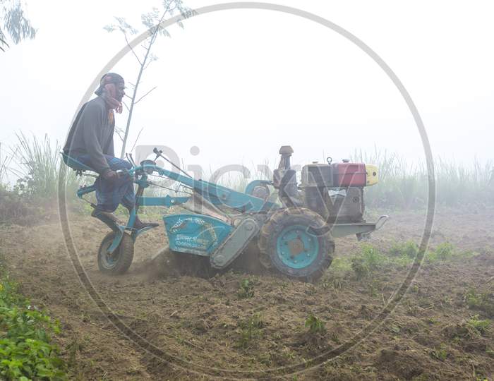 Bangladesh – January 06, 2014: On A Foggy Winter Morning, A Farmer Is Plowing His Land With A 2-Wheel Tractor At Ranisankail, Thakurgaon.