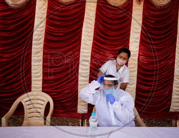 A nurse assists a doctor wear her face shield as they prepare to test police personnel for covid-19 during a health screening camp for the police forces in Bangalore, India.