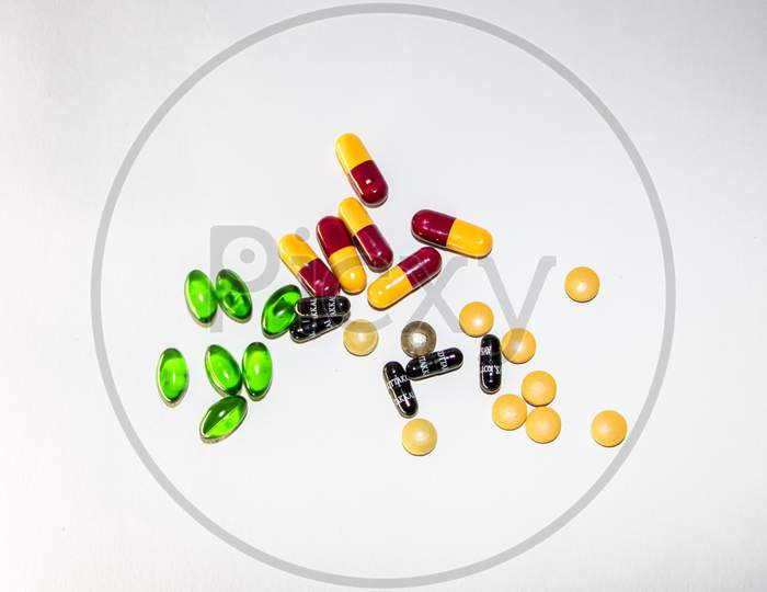 Pile of colorful tablets and capsule pills isolated on white background.