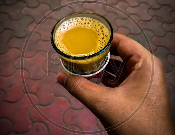 A Close Up Shot Of Hand Holding Glass Of Tea ( Chai )