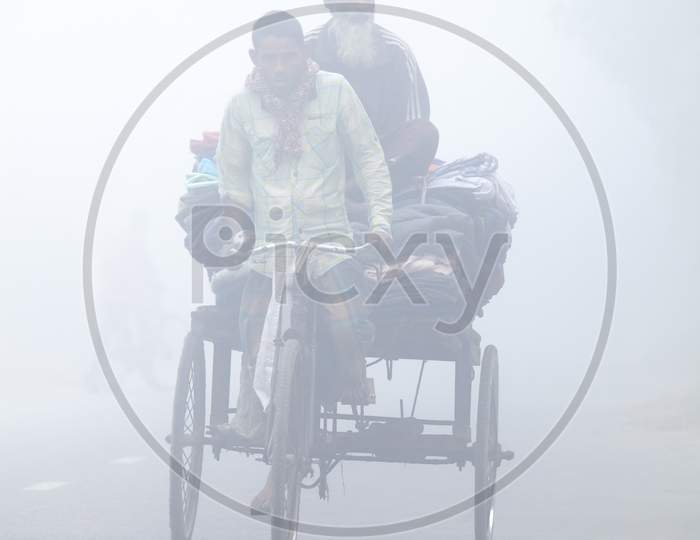 Bangladesh – January 06, 2014: On A Foggy Winter Morning, Some Village People Going To Work On A Bicycle Through The Foggy Streets At Ranisankail, Thakurgaon.