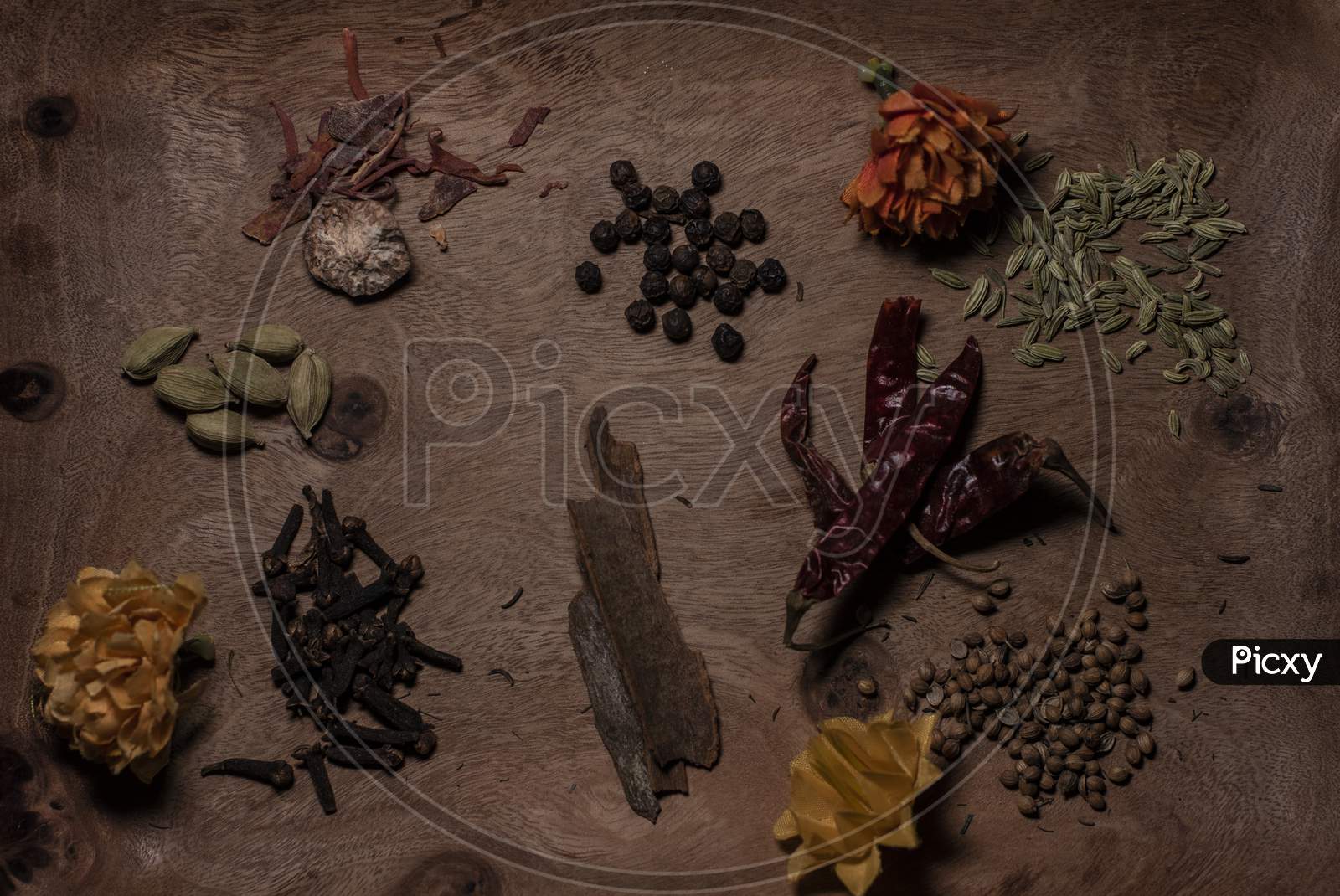 Top Down Image Of Different Whole Spices Decorated With Dried Flowers In A Wooden Background.