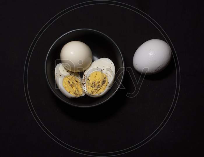 Boiled Eggs In A Bowl Along With A Raw Egg In Dark Copy Space Background. Food And Product Photography.