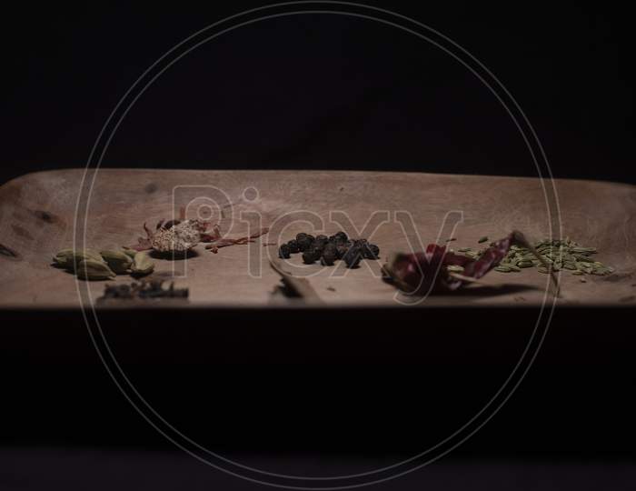 Different Whole Spices On A Wooden Tray In Dark Copy Space Background.