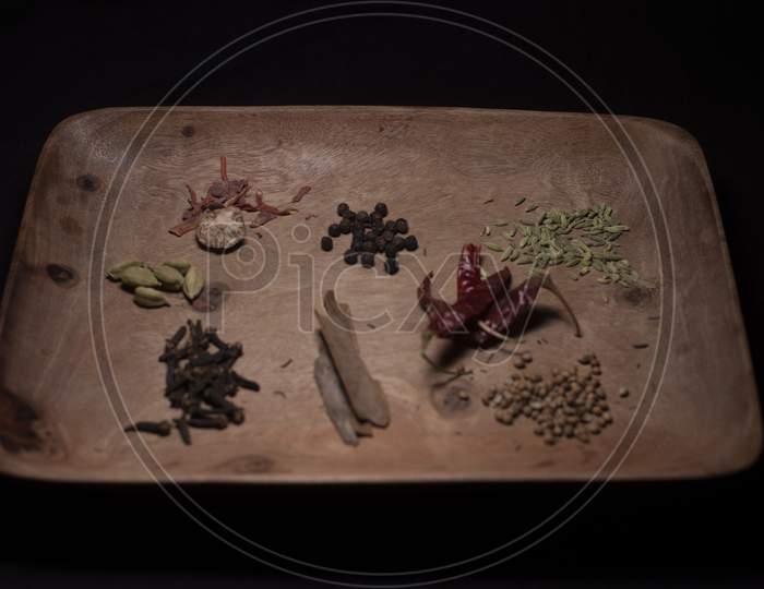 Different Whole Spices On A Wooden Tray In Dark Copy Space Background.