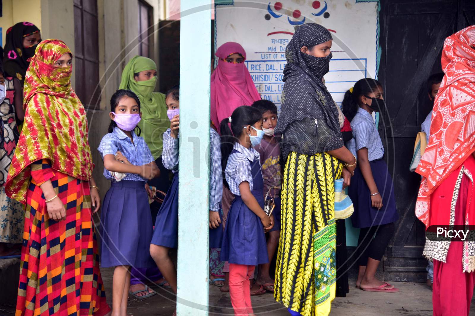 School Children Stand And Their Families Stand In Queue For Free Rice And Money To Be Given By The Volunteers During Nationwide Lockdown Amidst Coronavirus Or COVID-19 Pandemic in Nagaon on May 14 2020
