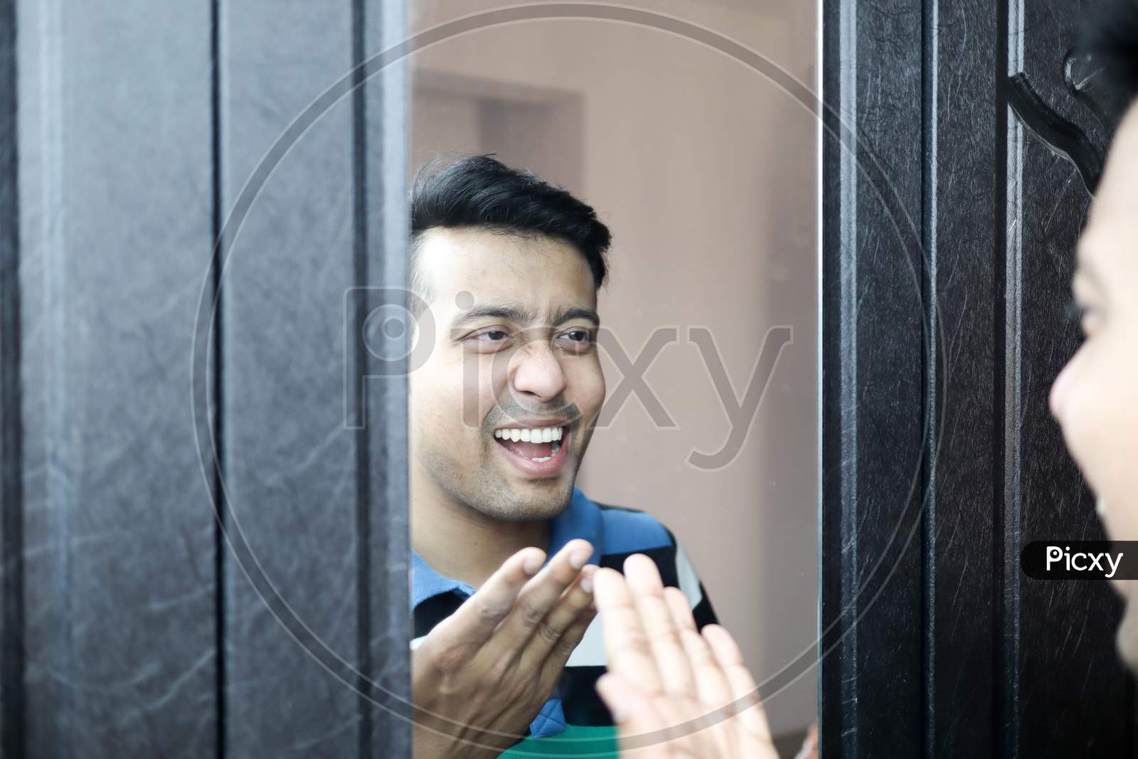 A Man Looking At His Reflection In Mirror And Laughing At Himself