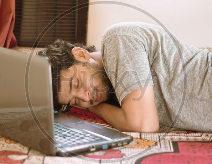 Tired Young Man Sleeping In Bed With Laptop - Hard Work, Laziness Of Working From Home Or Wfh During Coronavirus Or Covid-19 Lock Down Concept.
