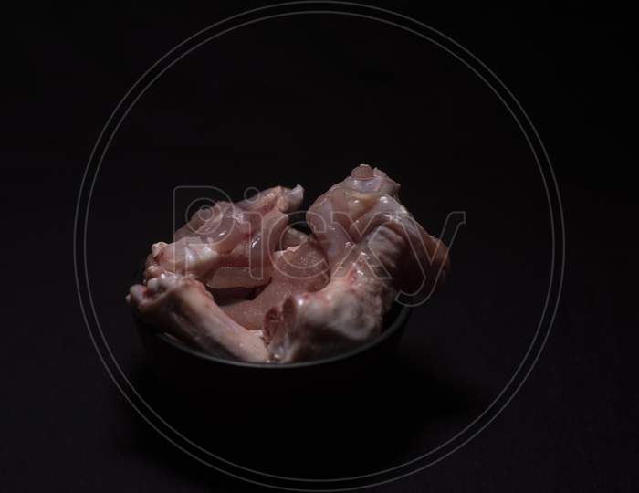 A Bowl Of Raw Chicken Pieces In A Dark Copy Space Background. Food And Product Photography.