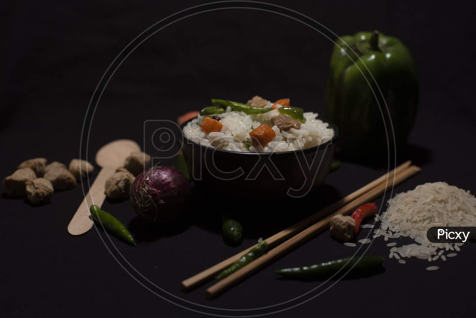 A Bowl Of A Steamed Rice And Vegetables Decorated With Veggies, Grains, Chopsticks And Spoon In A Black Copy Space Background. Food Photography.