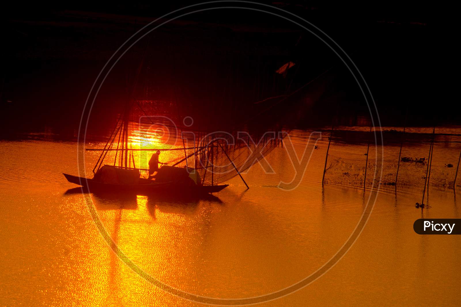 A Traditional Fisherman Catching The Fish Into The Golden Twilight At Sunset Time.