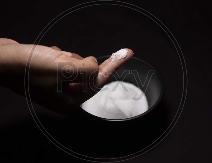 A Bowl Full Of Salt And A Pinch Of Salt In Dark Copy Space Background. Food And Product Photography.