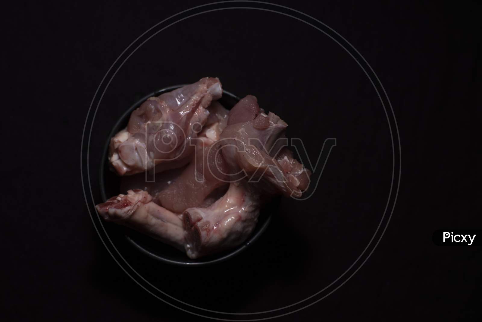 Top Down Image Of A Bowl Of Raw Chicken Pieces In A Dark Copy Space Background. Food And Product Photography.