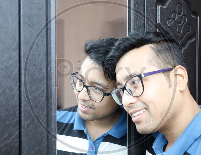 A Man In Eye Glasses And His Reflection In Mirror Smiling In Happy Mood