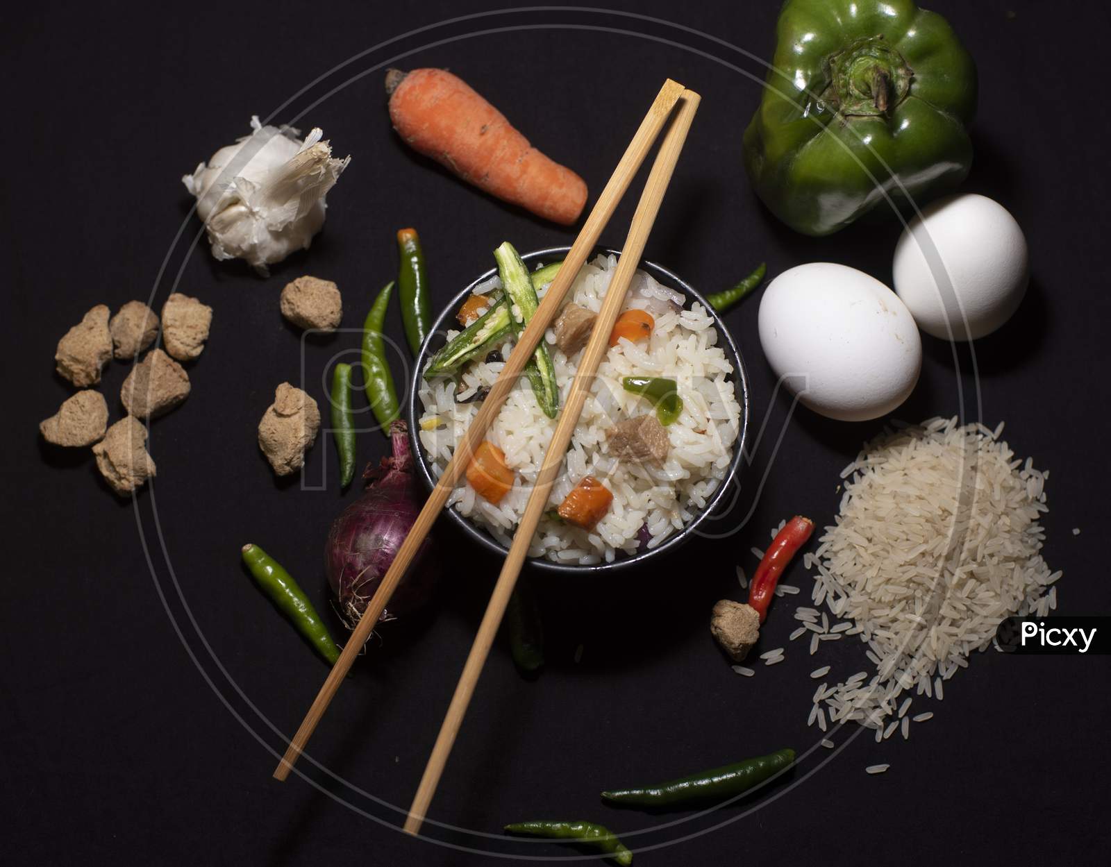 Top Down Image Of A Bowl Of A Steamed Rice And Vegetables Decorated With Veggies, Eggs, Grains, Chopsticks And Spoon In A Black Copy Space Background. Food Photography.