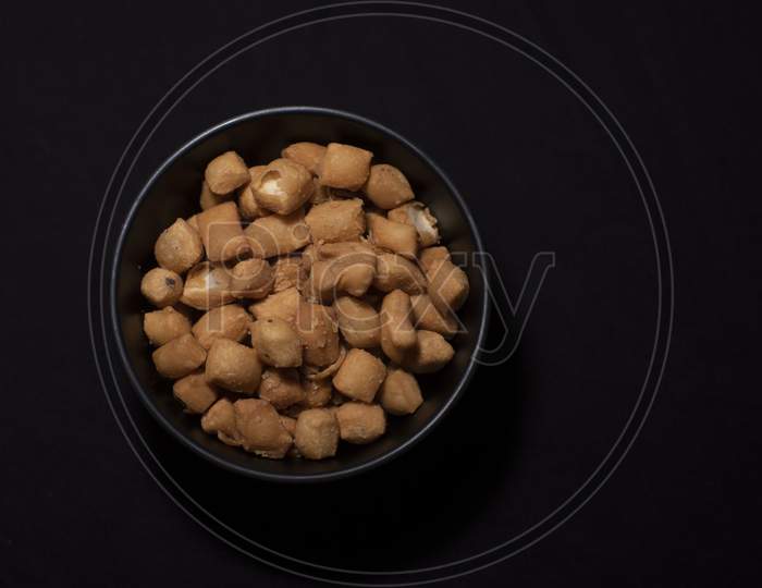 Top Down Image Of A Bowl Full Of Granular Snacks In Dark Copy Space Background. Food And Product Photography.