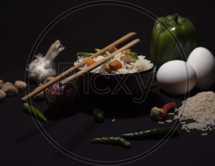 A Bowl Of A Steamed Rice And Vegetables Decorated With Veggies, Eggs, Grains, Chopsticks And Spoon In A Black Copy Space Background. Food Photography.