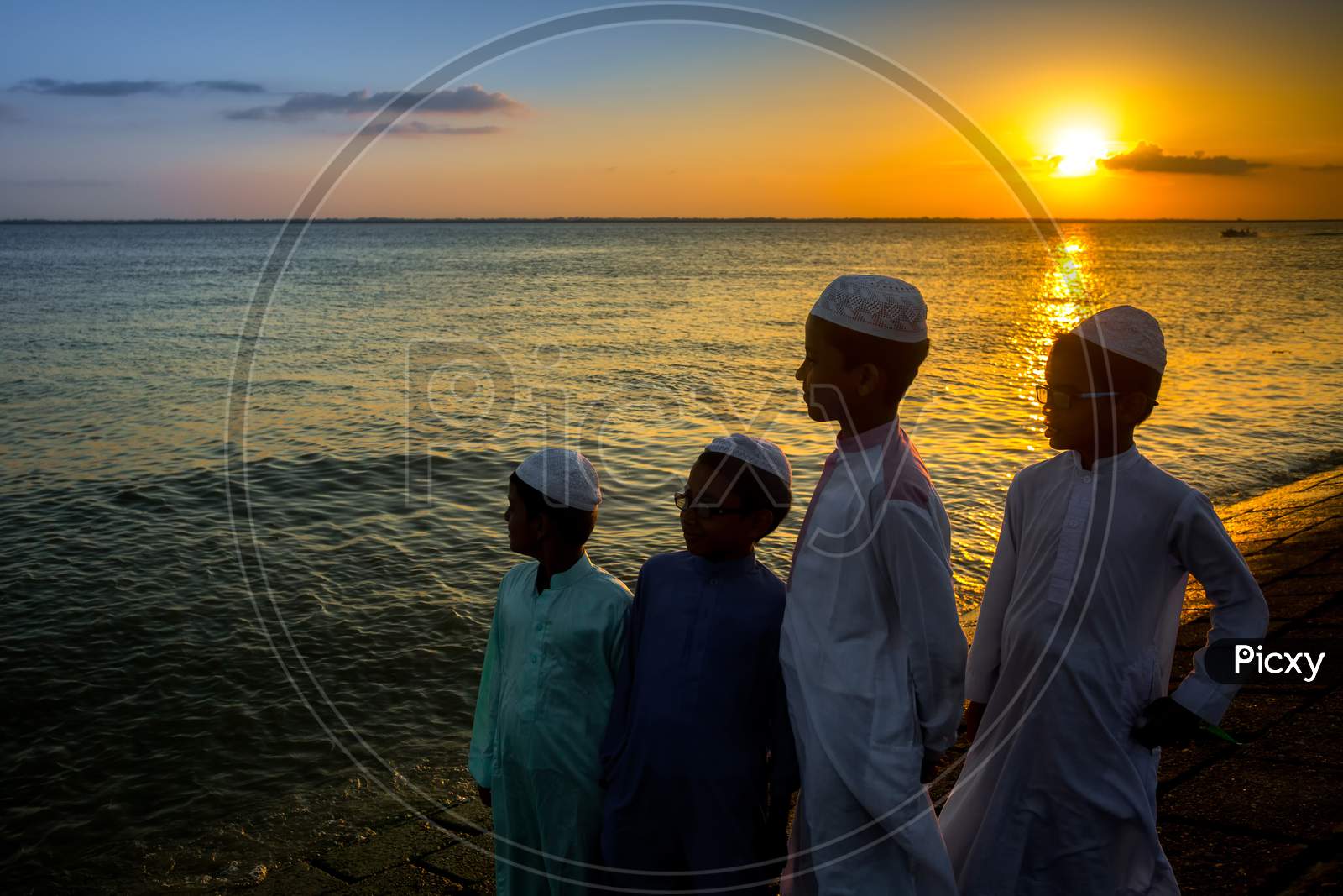 Bangladesh – June 22, 2019: Some Muslim Boys Are Standing By The Riverside Watching The Evening Sunset At Chandpur, Bangladesh.