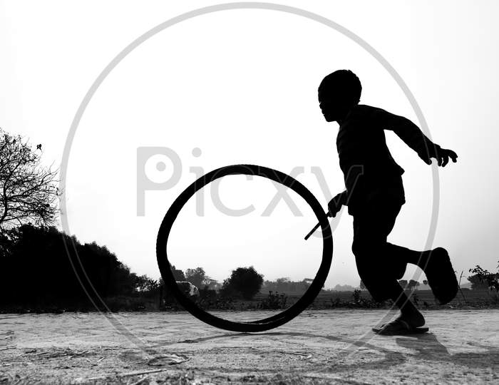 Bangladesh – January 24, 2020: A Restless Boy Is Playing On The Village Road With Old Discarded Tires At Savar, Dhaka, Bangladesh.