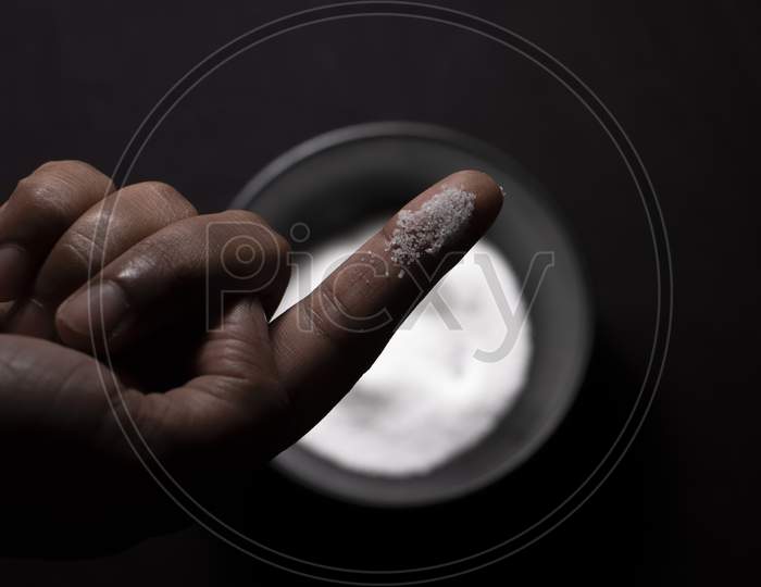 Top Down Image Of A Bowl Full Of Salt And A Pinch Of Salt In Dark Copy Space Background. Food And Product Photography.