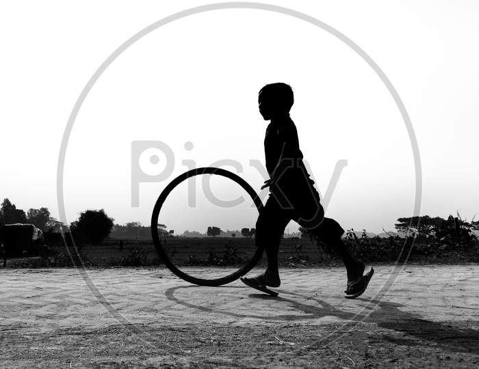Bangladesh – January 24, 2020: A Restless Boy Is Playing On The Village Road With Old Discarded Tires At Savar, Dhaka, Bangladesh.
