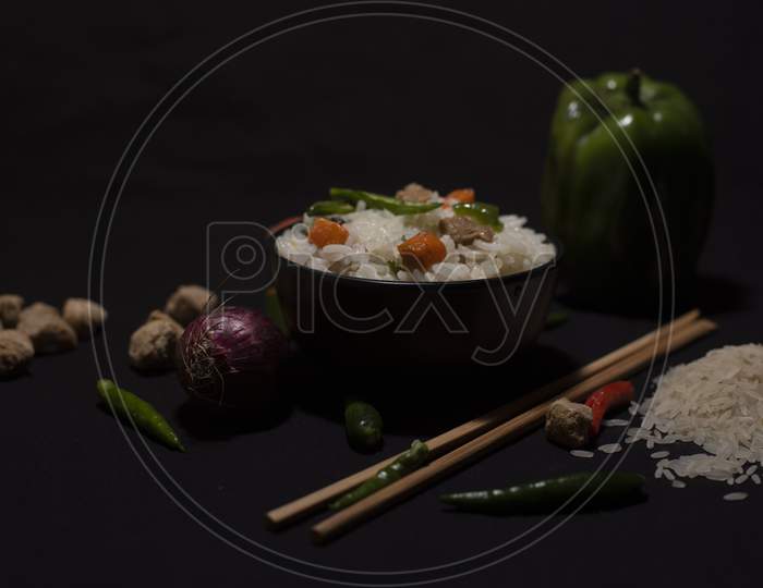A Bowl Of A Steamed Rice And Vegetables Decorated With Veggies, Grains, Chopsticks And Spoon In A Black Copy Space Background. Food Photography.