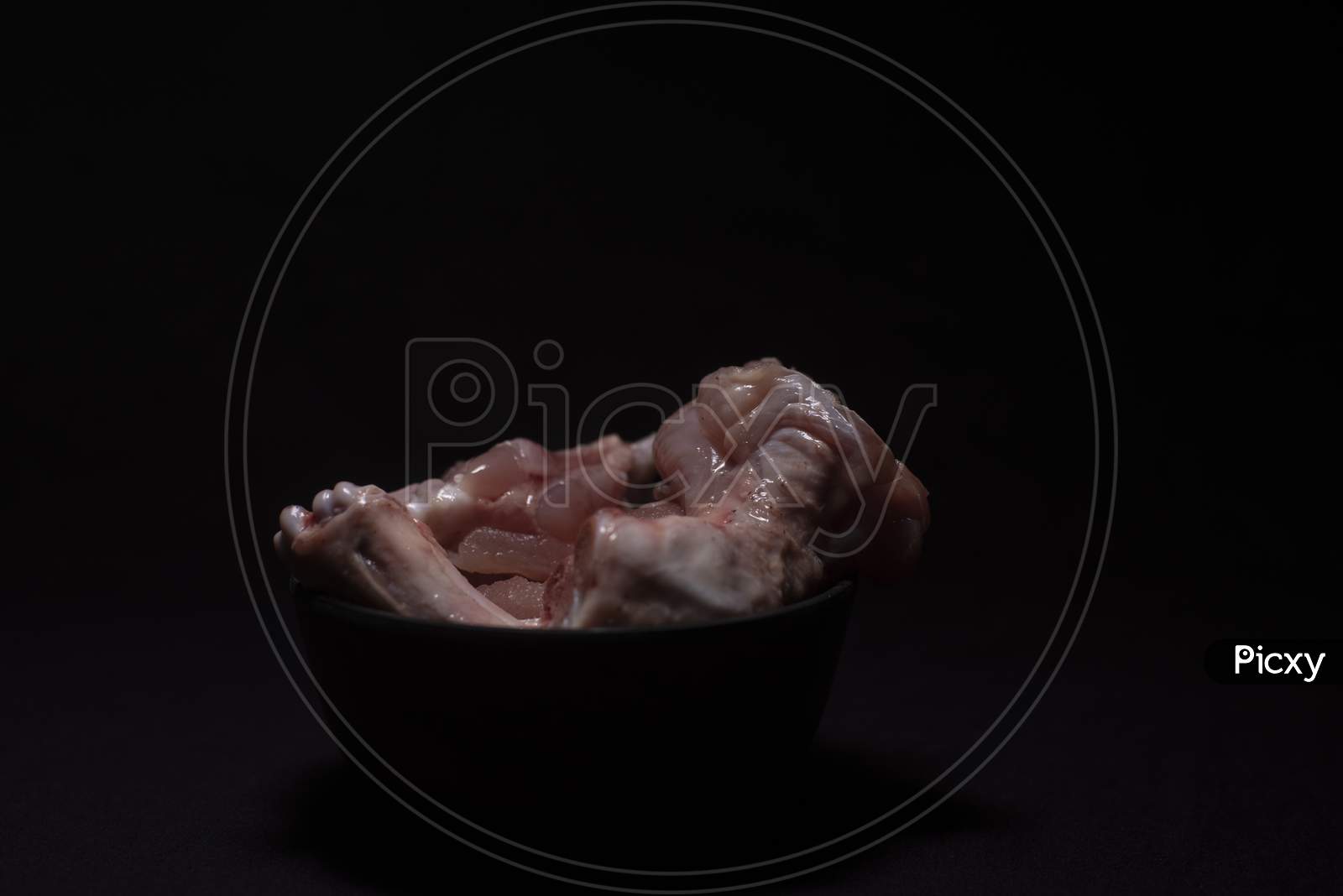 A Bowl Of Raw Chicken Pieces In A Dark Copy Space Background. Food And Product Photography.