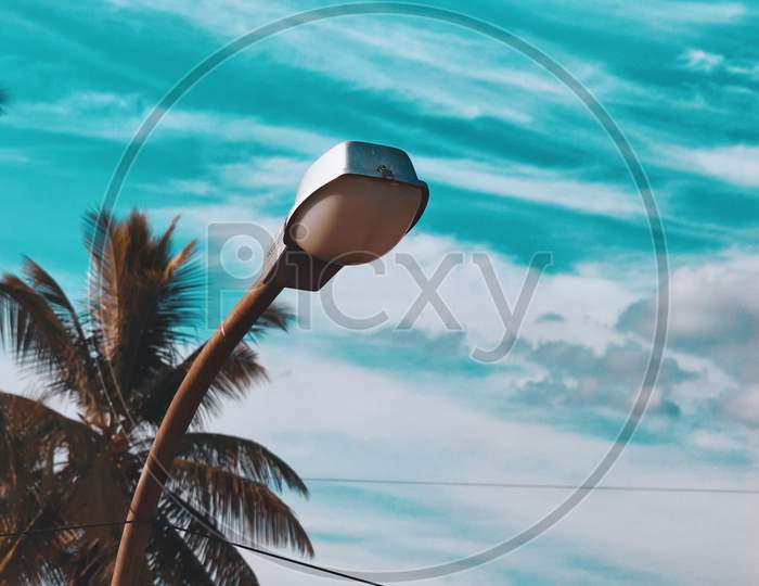 Lamp street lighting on the background of blue sky and a palm tree shallow depth in field