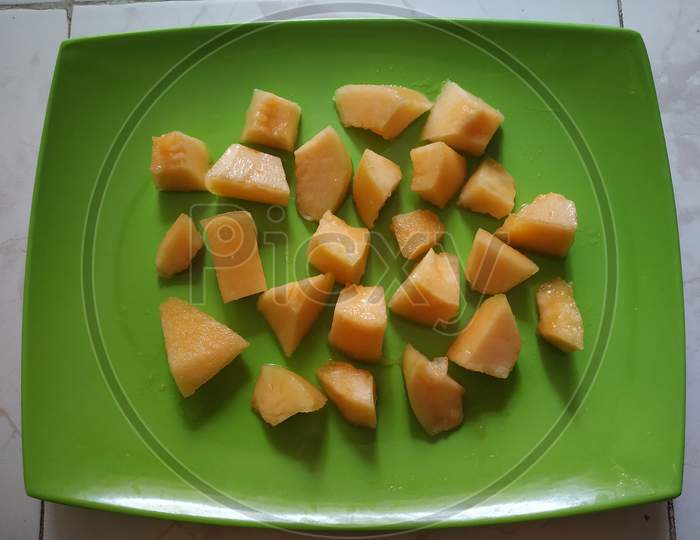 Top view of chopped melon slices in green plate