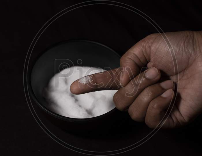 Top Down Image Of A Bowl Full Of Salt And A Pinch Of Salt In Dark Copy Space Background. Food And Product Photography.