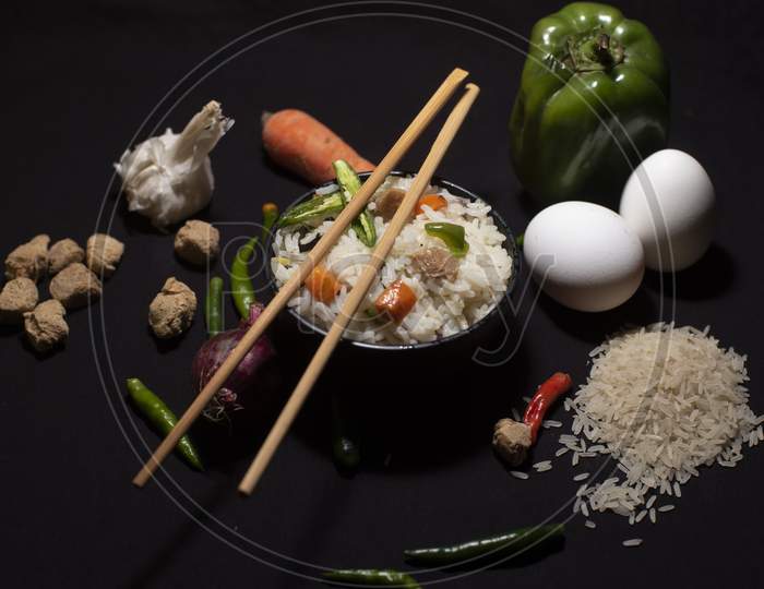 Top Down Image Of A Bowl Of A Steamed Rice And Vegetables Decorated With Veggies, Eggs, Grains, Chopsticks And Spoon In A Black Copy Space Background. Food Photography.