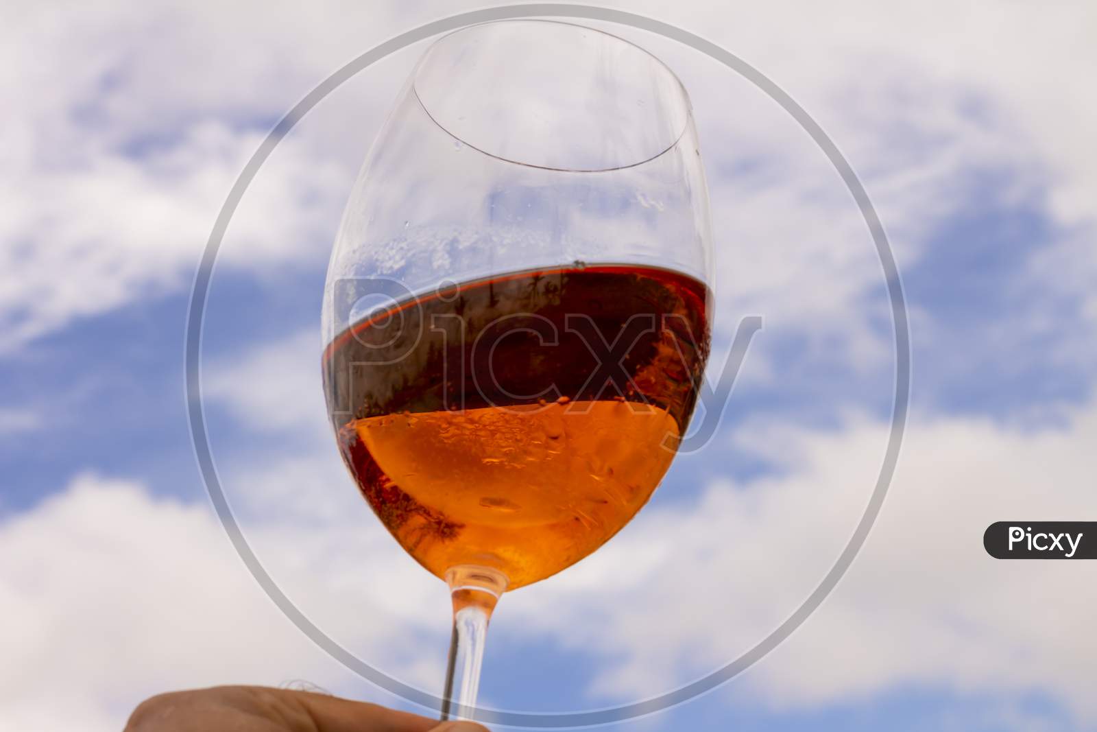 Crystal Glass With Fresh Rosé Wine For Making A Toast Raised To Heaven. Celebration Or Wealth Concept.