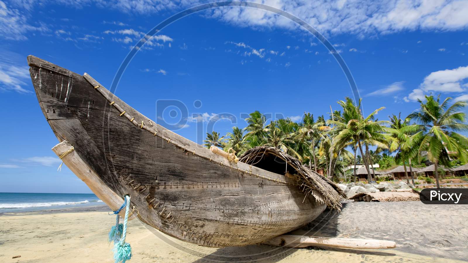 A modern wooden boat near the sea beach on dry sand with palm trees and blue sky