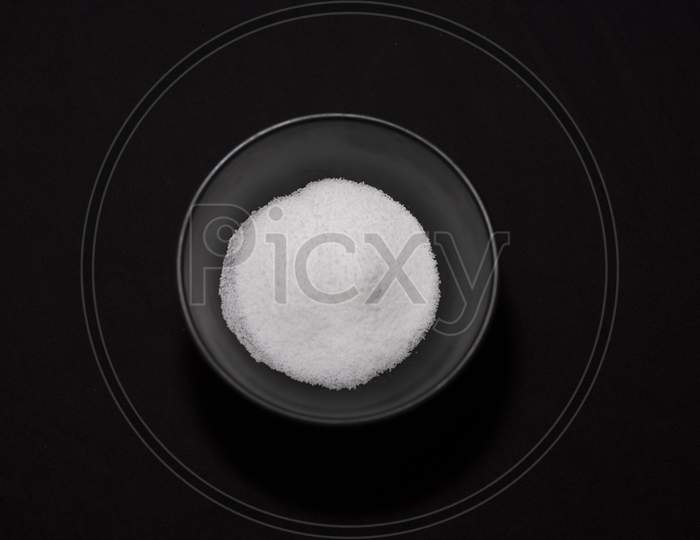 Top Down View Of A Bowl Full Of Salt In Dark Copy Space Background. Food And Product Photography.