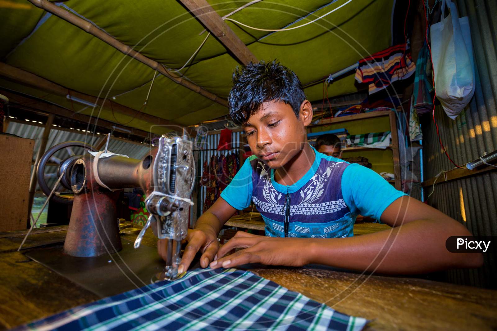 Bangladesh – October 28, 2019: A Young Boy Working As A Tailor Labor At Rural Village Tailor Shop, Chandpur, Bangladesh.