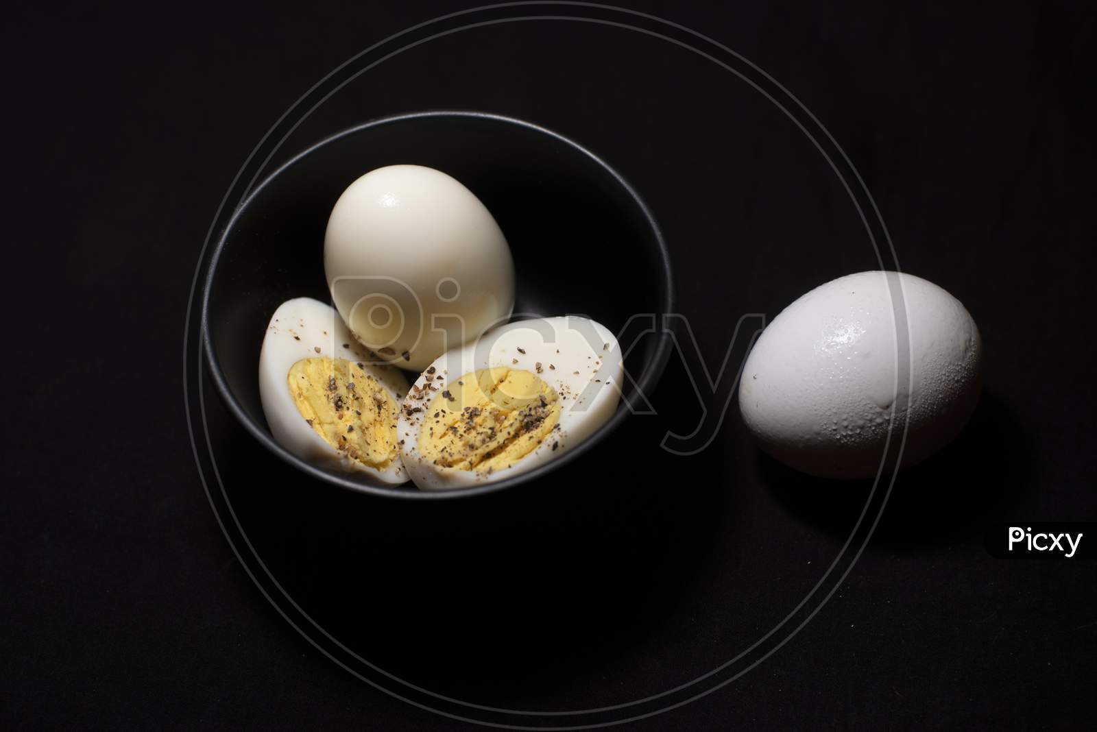 Boiled Eggs In A Bowl Along With A Raw Egg In Dark Copy Space Background. Food And Product Photography.