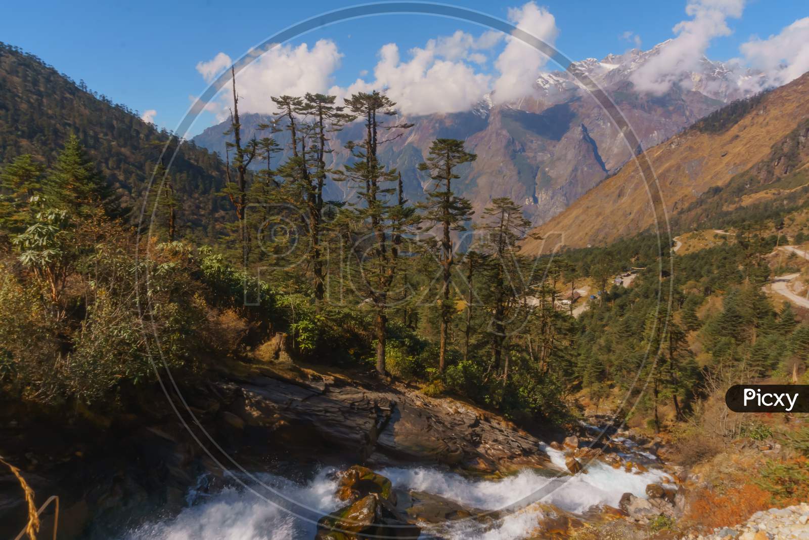landscape of cloud covered mountain range of Himalaya with a fountain an alpine forest in front