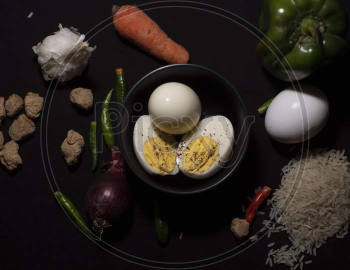 Top Down Image Of A Boiled Eggs In A Bowl Decorated With Cereals And Vegetables In Dark Copy Space Background. Food And Product Photography.