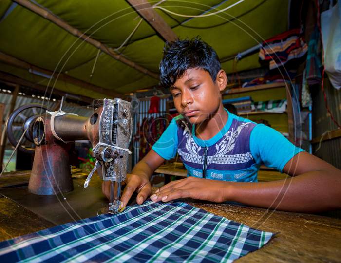 Bangladesh – October 28, 2019: A Young Boy Working As A Tailor Labor At Rural Village Tailor Shop, Chandpur, Bangladesh.