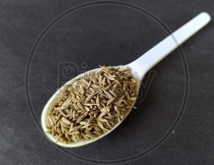 White cumin seeds in a spoon.