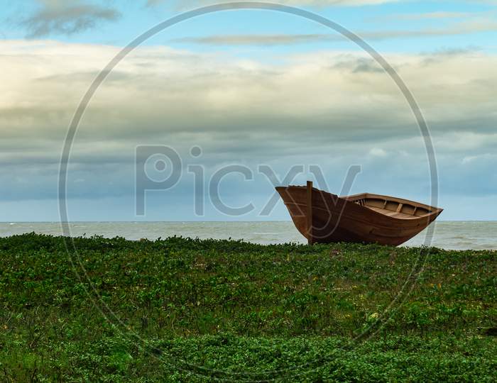 Beautiful Wooden Boat In Repair Leaning Against The Coastal Grass.