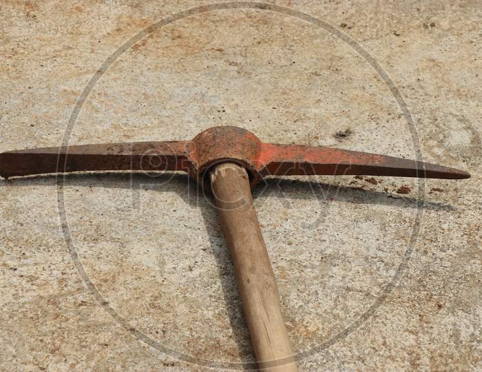 Old Pickaxe With Wooden Handle Kept In Concrete Floor