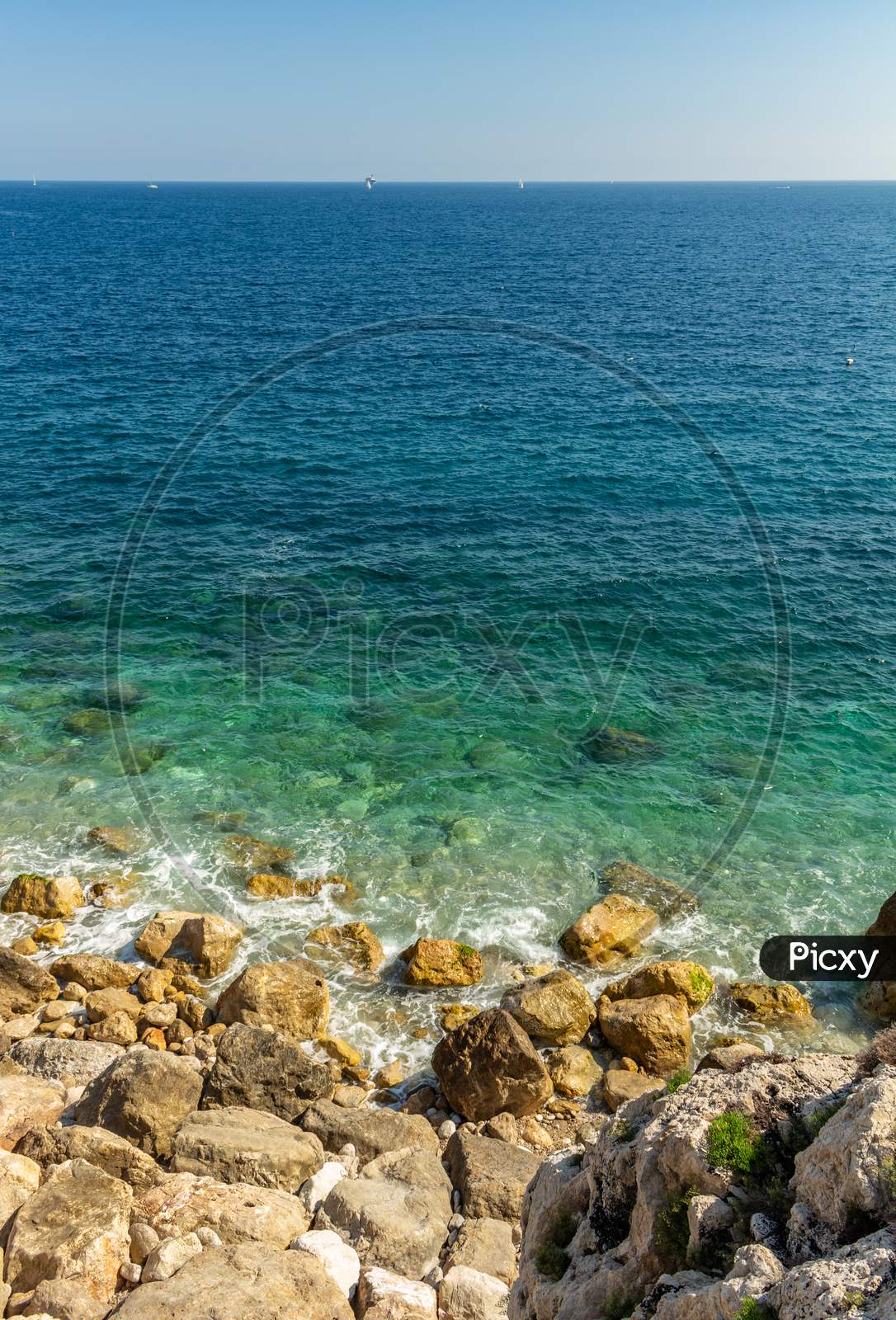 Beautiful View Of The Cliff Submerging Under The Crystal Clear Waters Of The Mediterranean Sea.
