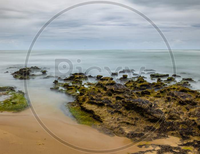 Rocks Covered With Marine Foam. Long Exposure On The Coast. Silk Effect In Sea Water.