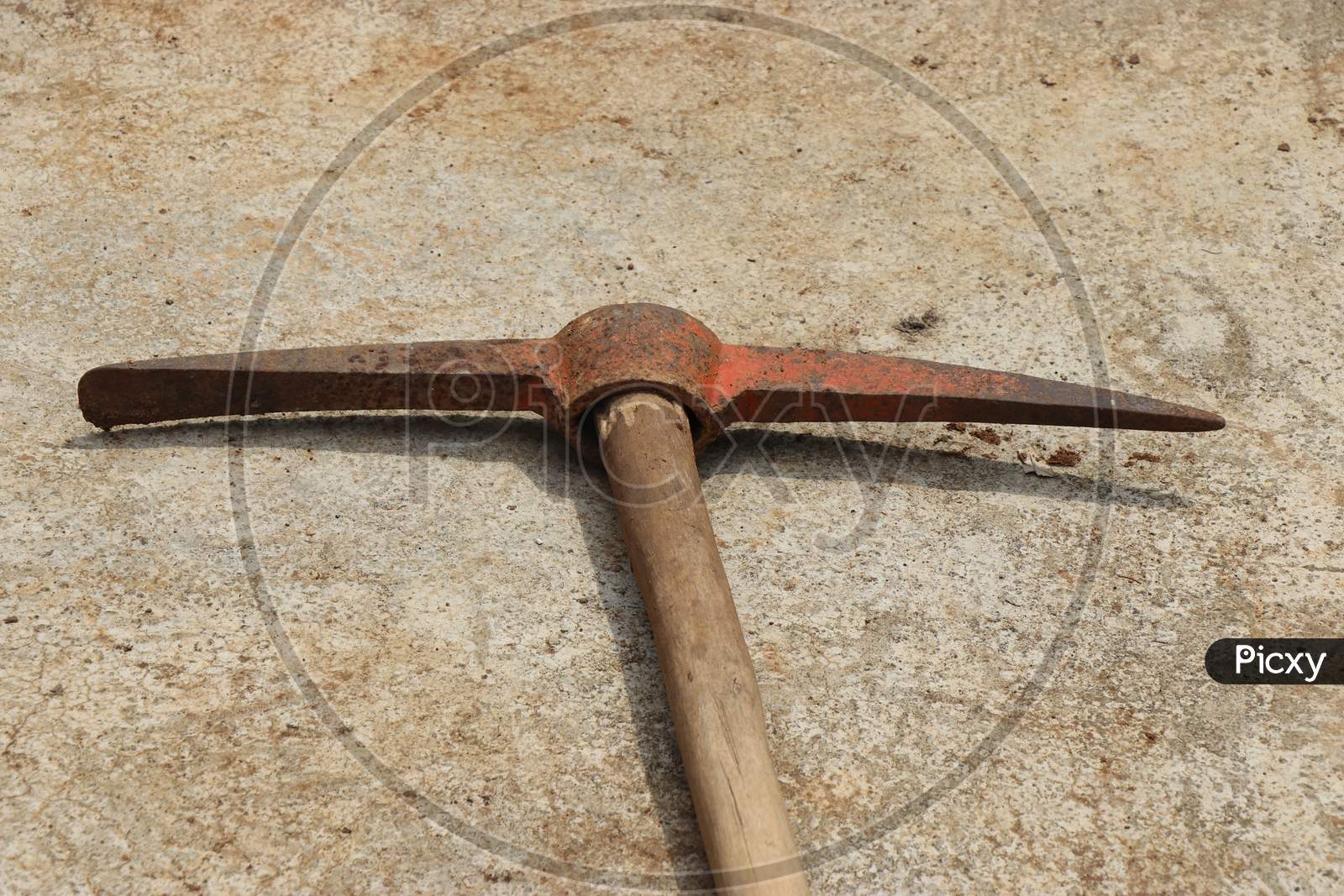 Old Pickaxe With Wooden Handle Kept In Concrete Floor