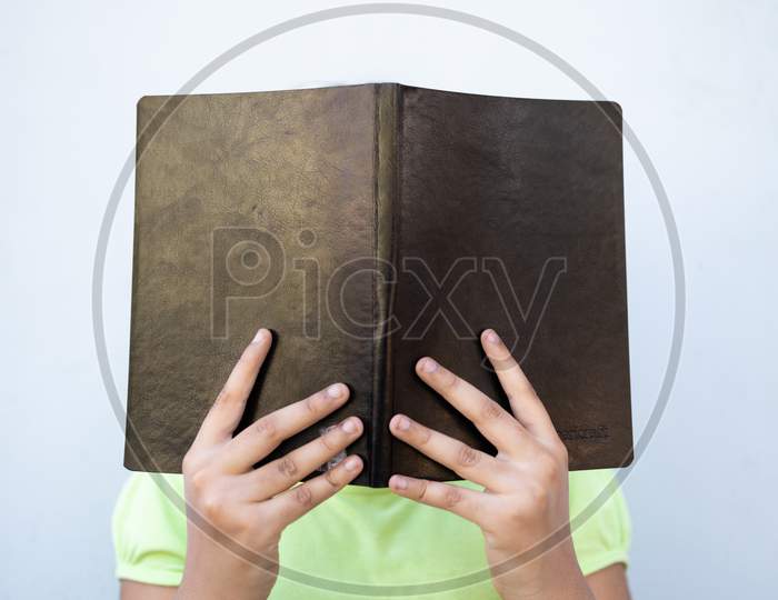 Child Reading A Book Holding In Front Her Face