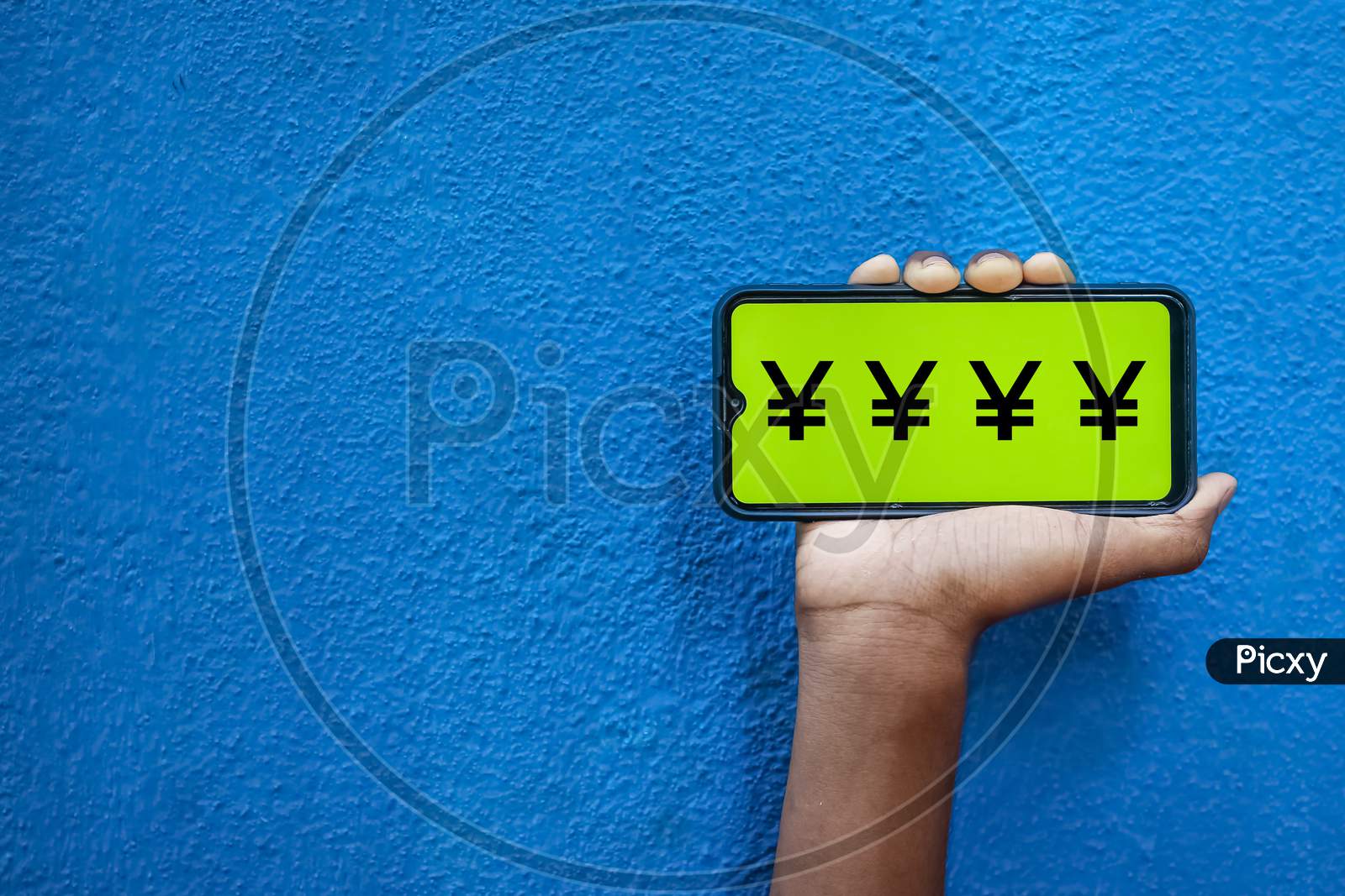 Japan Yen Currency Symbol Wording On Smart Phone Screen Isolated On Blue Background With Copy Space For Text. Person Holding Mobile On His Hand And Showing Front Of The Screen Symbol Of Japan Yen.