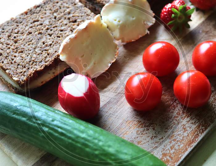 Close view on a healthy german breakfast with sandwiches tomatoes cucumbers and strawberries